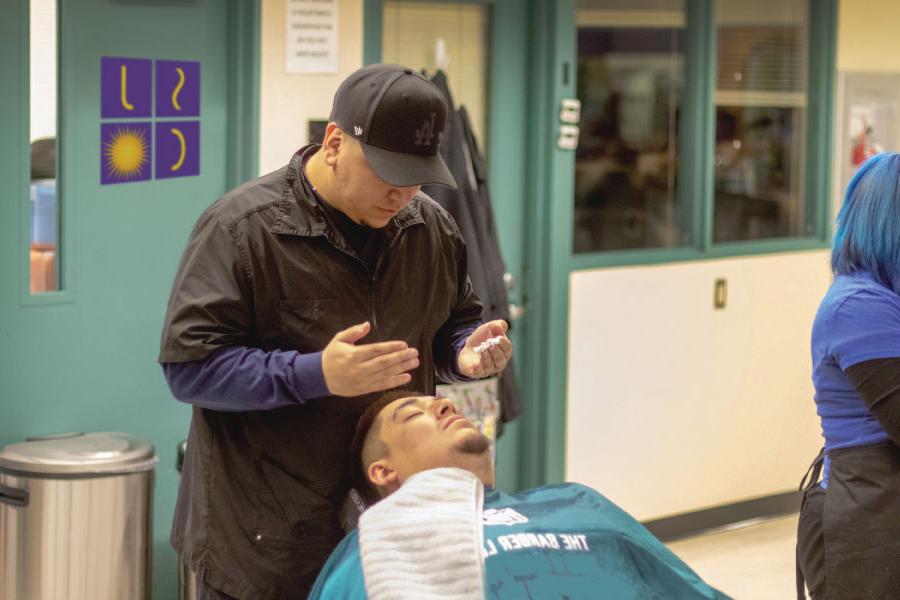 A San Juan College student preparing to put shaving cream on a man's face before a shave