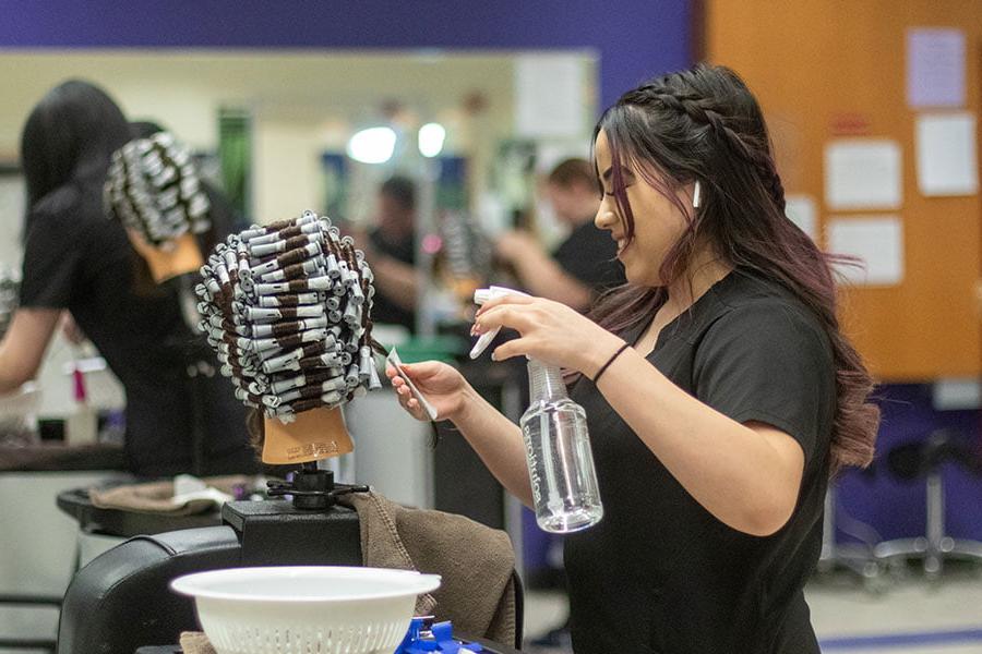 A San Juan College student practicing setting curls on a wig